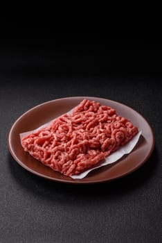 Stuffing or ground raw beef or pork with salt and spices on a black background