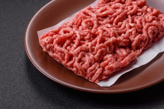 Stuffing or ground raw beef or pork with salt and spices on a black background