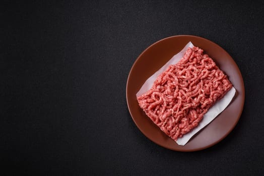 Stuffing or ground raw beef or pork with salt and spices on a black background