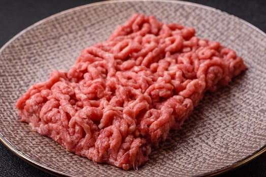 Stuffing or ground raw beef or pork with salt and spices on a black background