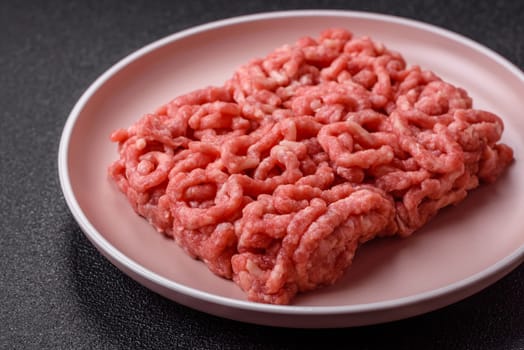 Stuffing or ground raw beef or pork with salt and spices on a black background