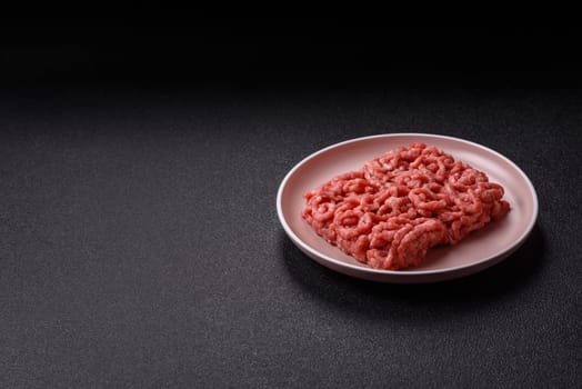 Stuffing or ground raw beef or pork with salt and spices on a black background