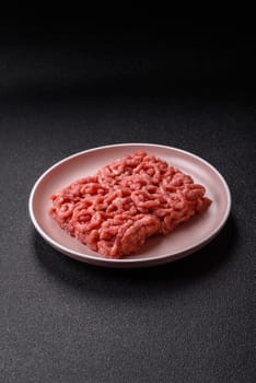 Stuffing or ground raw beef or pork with salt and spices on a black background