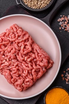 Stuffing or ground raw beef or pork with salt and spices on a black background