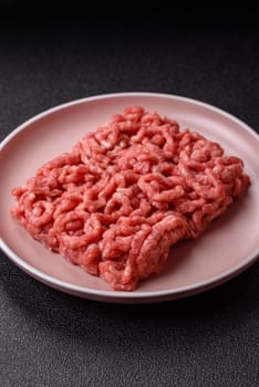 Stuffing or ground raw beef or pork with salt and spices on a black background