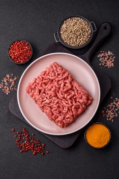 Stuffing or ground raw beef or pork with salt and spices on a black background