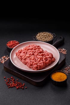 Stuffing or ground raw beef or pork with salt and spices on a black background