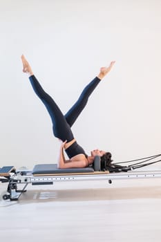 Asian woman doing pilates on reformer