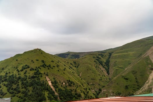 The mountains are covered in lush green trees and the sky is cloudy. The scene is peaceful and serene, with the mountains providing a beautiful backdrop