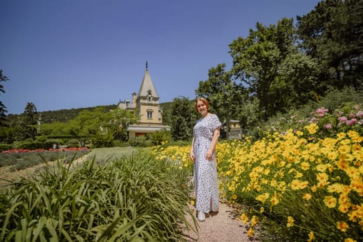 A woman is standing in a field of yellow flowers. She is wearing a white dress and smiling. The scene is peaceful and serene, with the bright yellow flowers adding a cheerful touch to the landscape