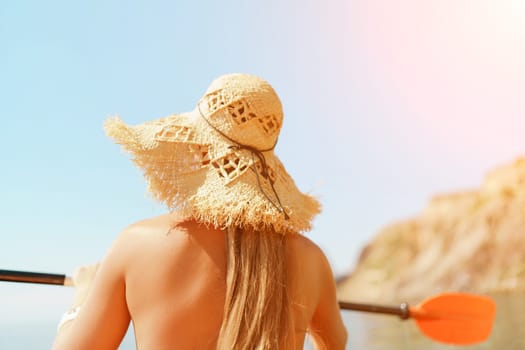 Woman in kayak back view. Happy woman with long hair in a swimsuit and hat floating in kayak on the sea. Summer holiday vacation. Summer holidays vacation at sea