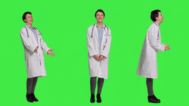 Portrait of general practitioner laughing at something against greenscreen backdrop, feeling joyful and confident with her healthcare expertise. Woman medic in white coat smiling in studio. Camera A.