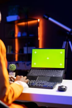 Teleworker in home office editing documents on mockup laptop, updating reports and files, typing text. Freelancer managing digital paperwork within file directories on green screen notebook