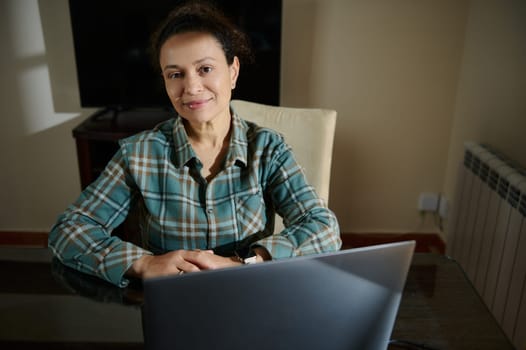 A professional woman confidently working from her home office, showcasing focus and productivity in a cozy, well-lit environment, representing remote work and online engagement.
