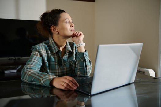 A woman sits at a desk with a laptop, thoughtfully planning her work in a serene home office. The scene highlights inspiration, focus, and dedication in a calm and professional setting.