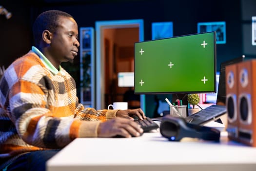 Black web developer handling database servers for safety with green screen, writing code on terminal window next to isolated chroma key. Programming language for machine learning.