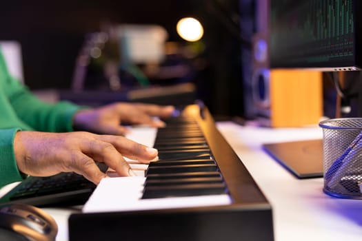 Songwriter performing a song on electronic piano keyboard, editing the audio files in post production. Artist technician mixing and mastering tracks on stereo console, musical notes. Close up.