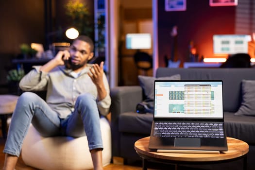 Black man teleworking from home uses his laptop to track stock exchange rates, does trade analysis for financial growth. Monitoring market trends, candlestick charts and profit statistics.
