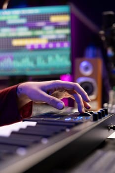 Audio engineer mixing and mastering music on daw software interface, creating cool modern tunes with acoustics and equalizer. Artist recording songs on soundboard panel in his home studio.