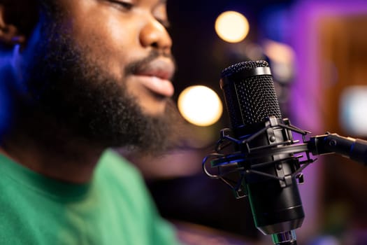 Singer performing his new track creation on a microphone, manipulates his audio files recordings with mixing and mastering techniques. Artist composer operates on stereo equipment. Close up.