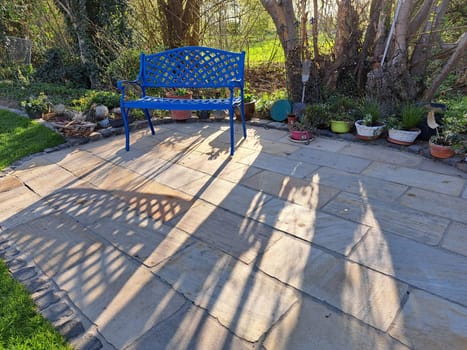 blaue Bank aus Gusseisen auf einer kleinen Terrasse
