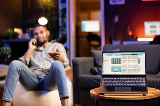 African American trader works from home using laptop to study stock prices, monitoring candlestick charts and exchange rates. Young focused investor analyzes profit and market liquidity.