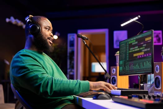Artist playing electronic piano keyboard to record sounds and use mixing techniques, editing recordings in home studio. Musician songwriter operating on electronic synthesizer gear.