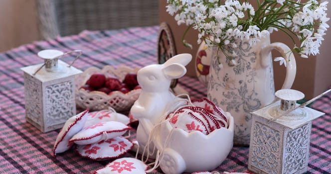 Springtime blooms enhance the Easter decorations displayed on a charming table setting. A white rabbit figurine and delicate floral arrangements bring festive cheer, perfect for seasonal celebrations.