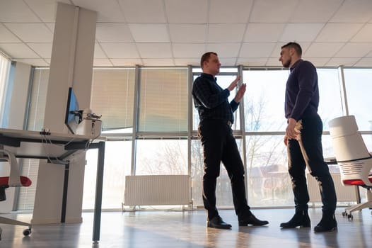 Two Caucasian men talking at work in the office