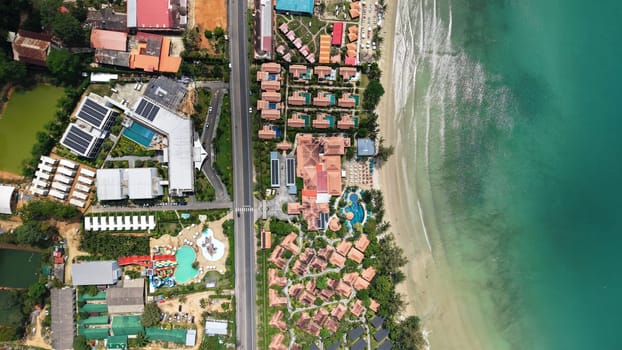 Aerial perspective showcasing a coastal resort with lush greenery, vibrant buildings, and a pristine beach. The image highlights the contrast between urban development and natural beauty