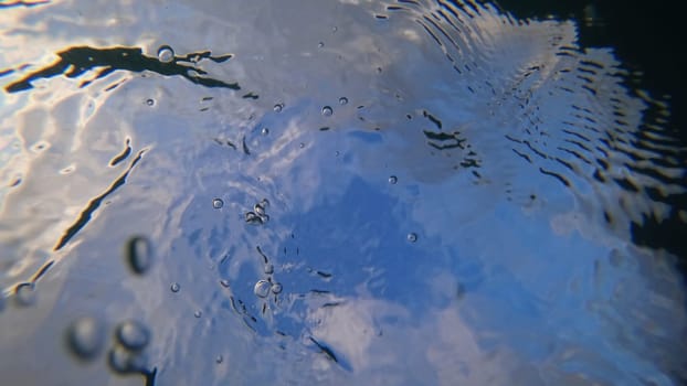 Capturing an underwater scene with air bubbles rising gracefully to the surface, creating a stunning pattern while reflecting the vibrant sky and fluffy clouds above
