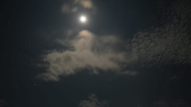 Bright moon illuminating the dark night sky, casting its glow through wispy clouds and creating a stunning celestial scene filled with beauty and tranquility