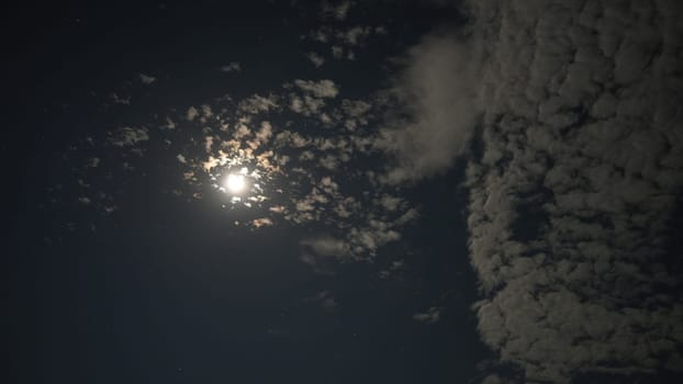 Bright moon illuminating the night sky, casting a soft glow through scattered clouds, creates a dramatic and ethereal atmosphere, inviting a sense of tranquility and wonder