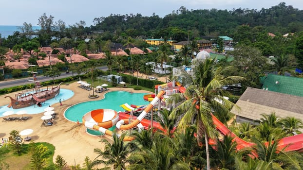 Aerial view captures the vibrant water slides, pools, and surrounding lush landscape of a tropical resort, offering a captivating glimpse into vacation fun and relaxation