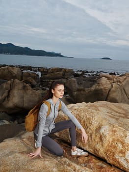 A young woman in activewear squats on a rocky beach, embodying determination and a love for nature Capturing the essence of adventure and healthy living, this image is perfect for fitness, wellness, and lifestyle themes
