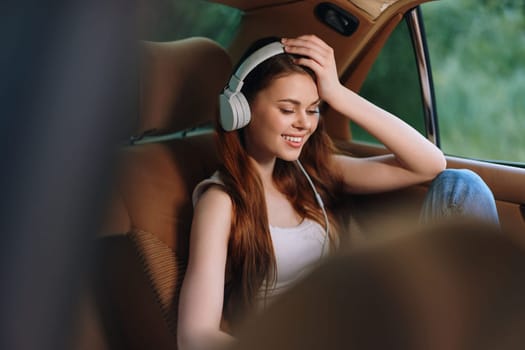 A cheerful young woman with long hair is sitting in a car, wearing headphones and smiling while listening to music. The soft, warm colors enhance a relaxed atmosphere, perfect for lifestyle and music