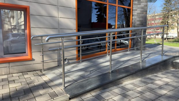 Ramp for entering building for people with disabilities and parents with baby carriage. Convenient entrance with lifting ramp for comfortable ascent. Accessible environment in modern city