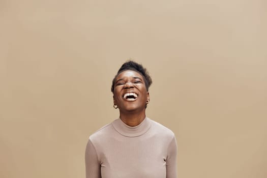A joyful black woman dressed in a light sweater smiles broadly, showcasing her happiness against a soft beige background This image captures the essence of joy and positivity, ideal for promoting we