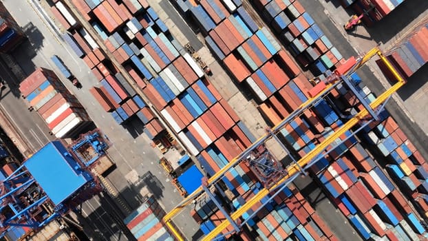 Capturing an aerial view of a container ship being loaded with cargo at a bustling commercial port, showcasing the dynamic logistics operation