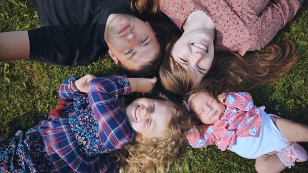 Cheerful family members forming circular huddle on verdant lawn, sharing warm embraces and bright smiles during outdoor bonding moment