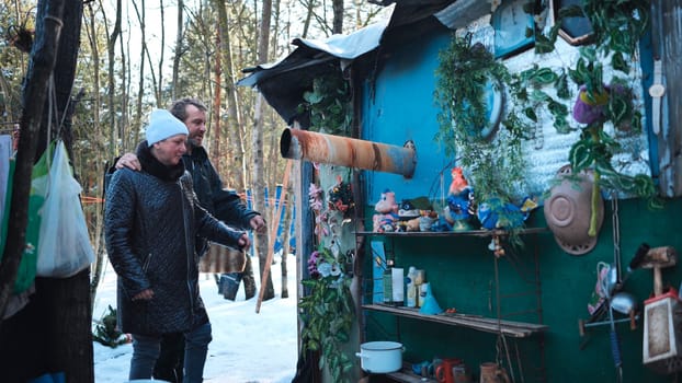 Social worker providing emotional support to homeless individual near temporary shelter amid winter woodland setting