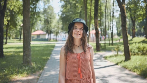 Happy teenager walking through a vibrant park, enjoying a sunny summer day, radiating joy and carefree spirit with a bright smile