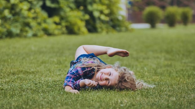 Laughing child rolling green lawn, expressing pure happiness during sunny family outdoor playtime with carefree energy