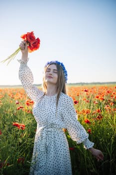 Radiant female standing amid golden poppy field, wearing delicate flower crown and holding vibrant red blooms during sunset glow