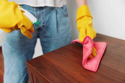 Woman in yellow gloves cleaning wooden table with rag and cleaning solution. cleaning concept, household chores, hygiene maintenance.