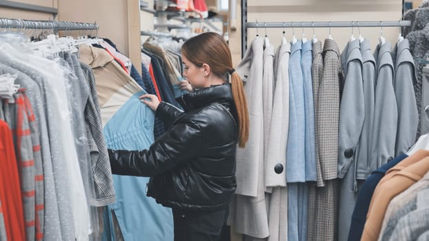 Customer browsing trendy clothes in a fashion store, examining various garments on hangers while searching for the perfect outfit