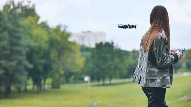 Professional woman controlling drone while flying through verdant urban greenery, blending work technology with outdoor recreation