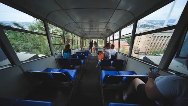 Tourists riding funicular in vladivostok, capturing panoramic city landscape with golden bridge stretching across horizon