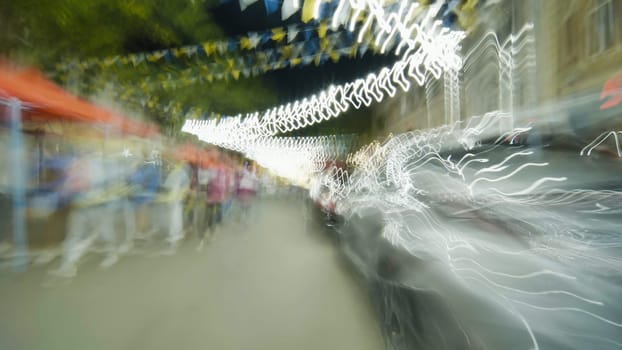 Light trails created by moving cars illuminating a night market with festive flags overhead