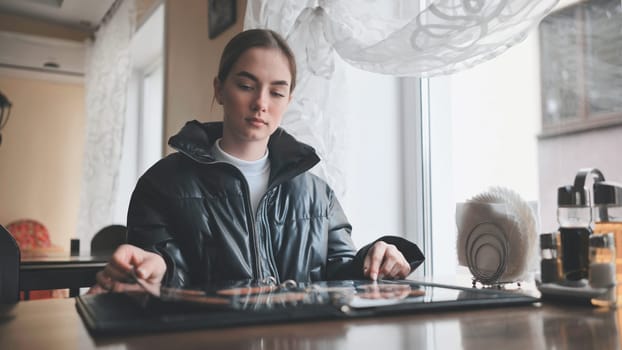 Customer sitting at a table in a cafe, browsing the menu and deciding on food options for lunch or dinner while enjoying the ambiance